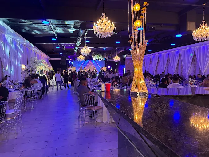 Live event with blue ambient lighting, guests dining, and decorative gold vase at Lavender Venue