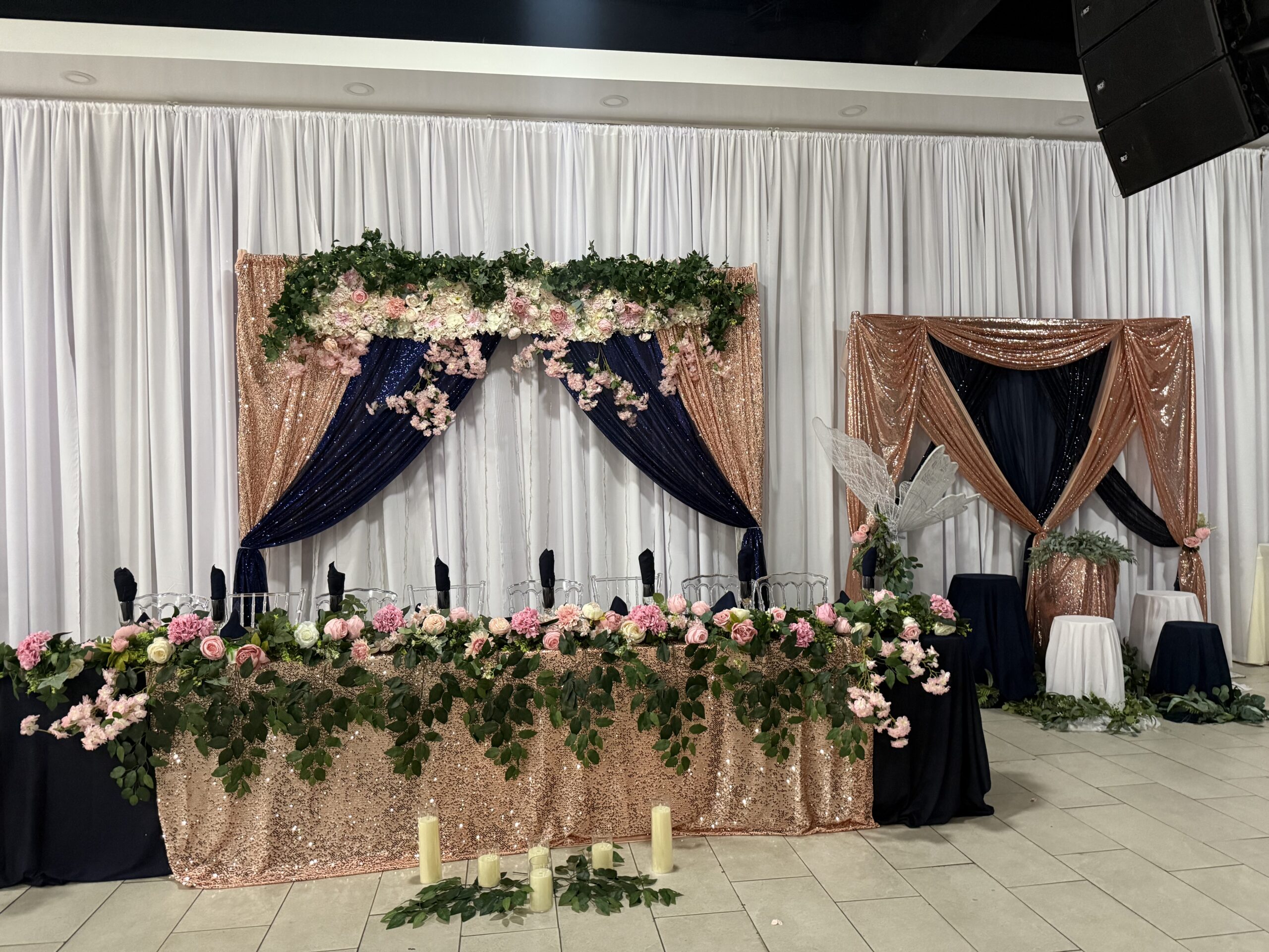 Rose gold sequin head table with navy draping and cascading florals at Lavender Venue