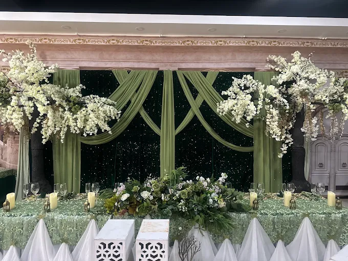 Elegant sage green wedding backdrop with white cherry blossoms and candles at Lavender Venue