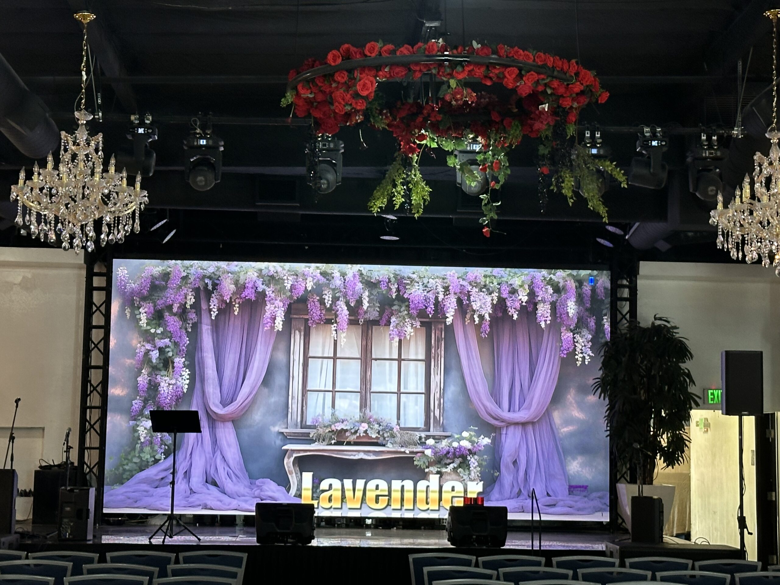 Professional stage with large LED screen displaying lavender florals and hanging rose wreath at Lavender Venue